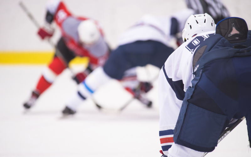 The hockey player is waiting for the puck to play.